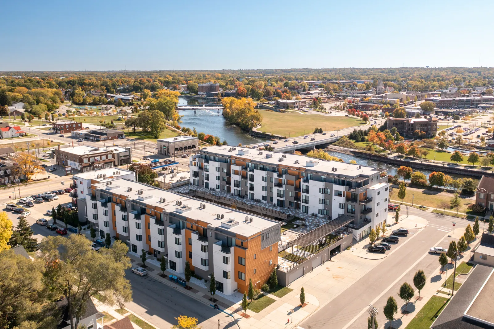 River Rock Condominiums from the air in autumn, on the north bank of the St. Joseph River, with the bridge, the parks, and downtown Mishawaka beyond.