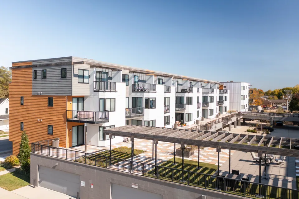 The Level 2 courtyard at River Rock on the garage roof, with its pergola, lawn, and seating, and the building behind.