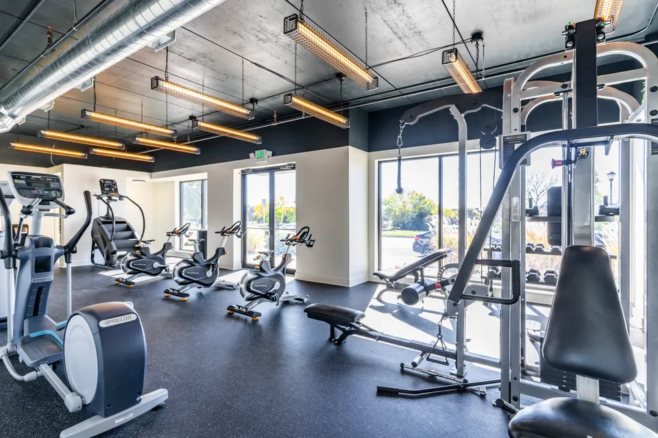 The resident fitness center at River Rock, with cardio machines, spin bikes, and a cable machine by the windows.
