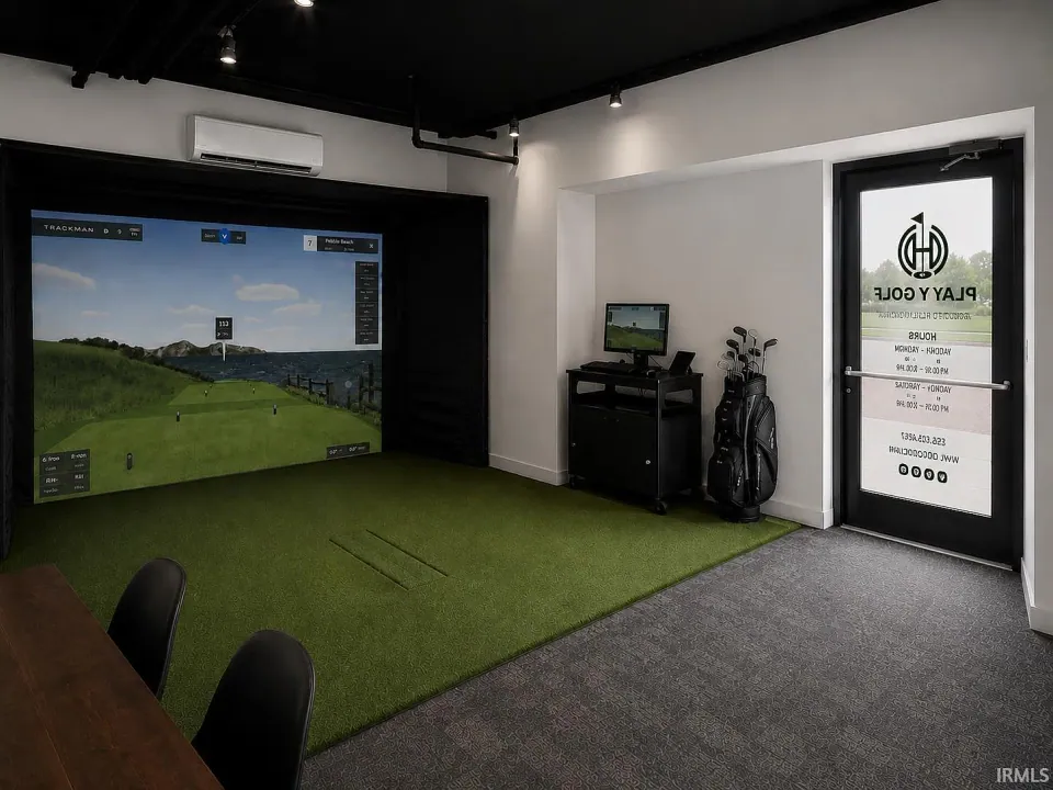The golf simulator at River Rock: a screen showing a fairway, a turf hitting mat, a golf bag, and the door to the room.