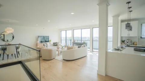 The great room of a two level River Rock residence seen from the upper landing, over the glass rail, with the seating, the fireplace, and the window wall beyond.
