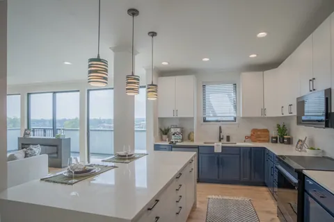 A River Rock kitchen with a white quartz island, navy cabinetry, pendant lights, and the St. Joseph River through the window.