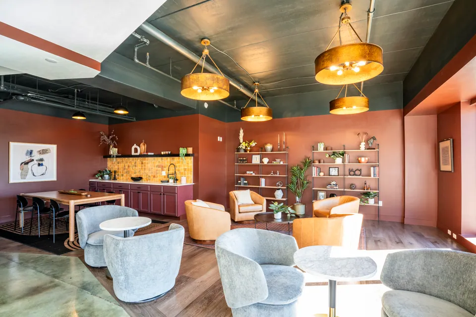 The resident lounge at River Rock, with a long table, armchairs, shelves, and a kitchenette.