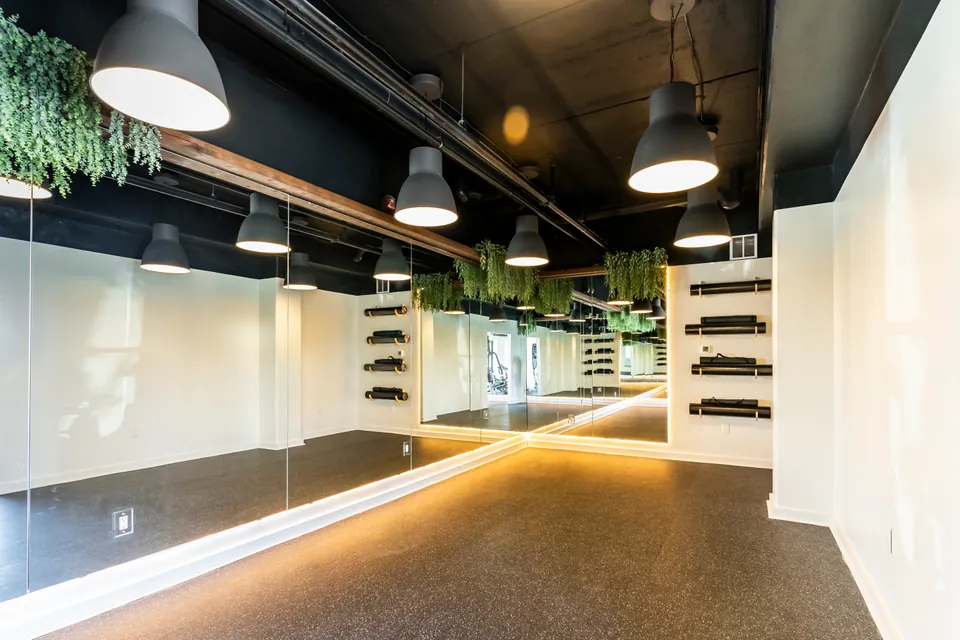 The yoga room at River Rock, with a mirrored wall, hanging plants, and mat racks.